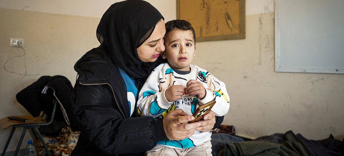 28岁的黎巴嫩境内流离失所者Sahar,是一名28岁的黎巴嫩妇女,她抱着她的4岁儿子穆罕默德在一间教室里.图片描绘了流离失所的情感代价和家庭在集体庇护所面临的困难生活条件.