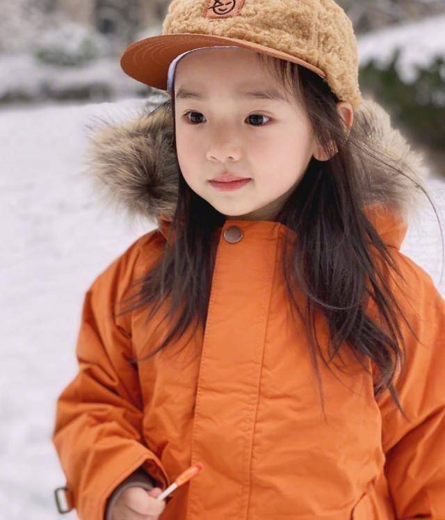 董璇女儿终于肯笑了穿橘色小袄配洋帽玩雪手拿棒棒糖脸型像爸
