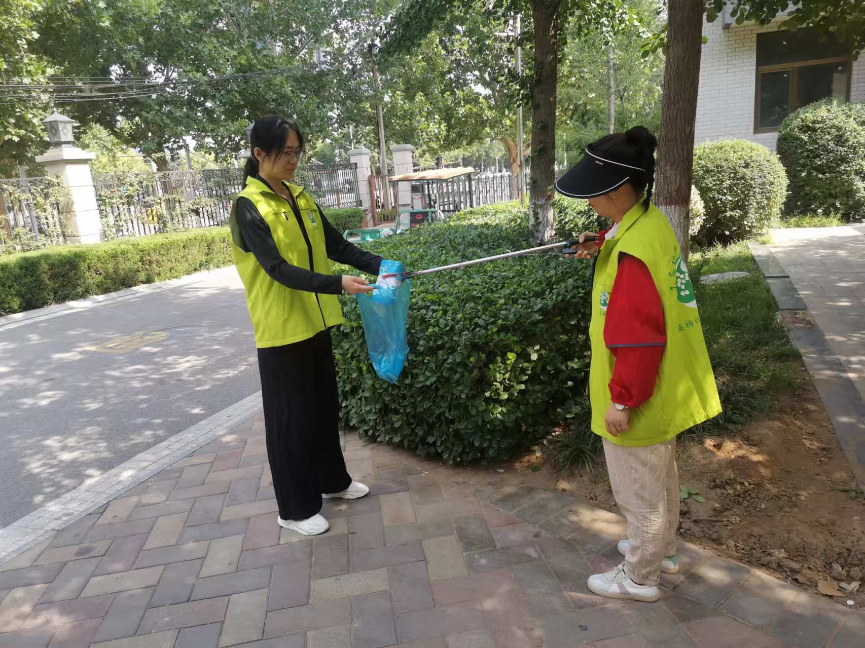 图为实践队员帮助社区工作人员捡垃圾.图为实践队员张贴物业信息.