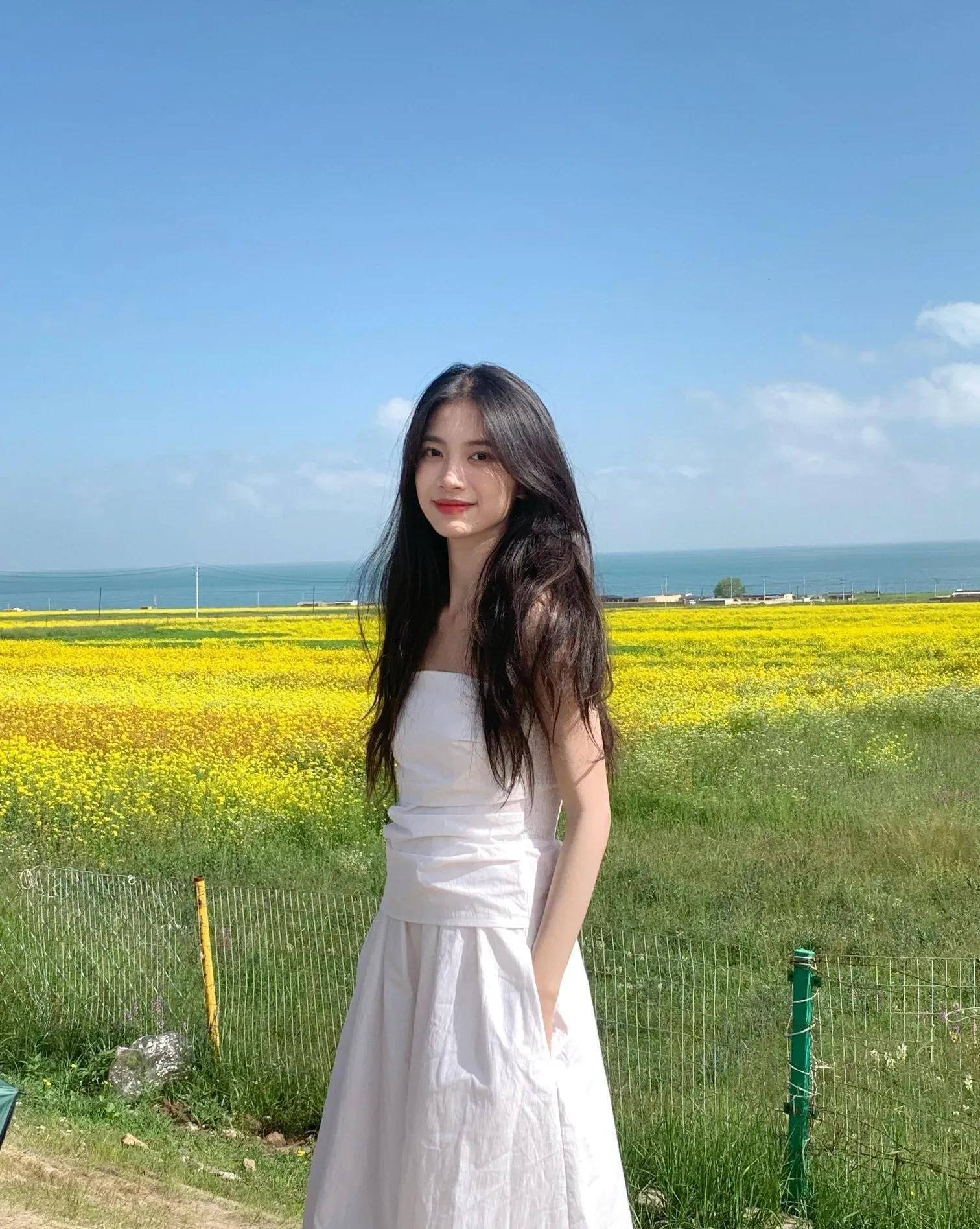 阳光下的微笑:美丽女子油菜花田边摄影