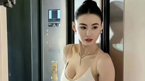 被张柏芝的上班图惊艳了！穿低胸吊带裙盘发，怕走光要用手捂住