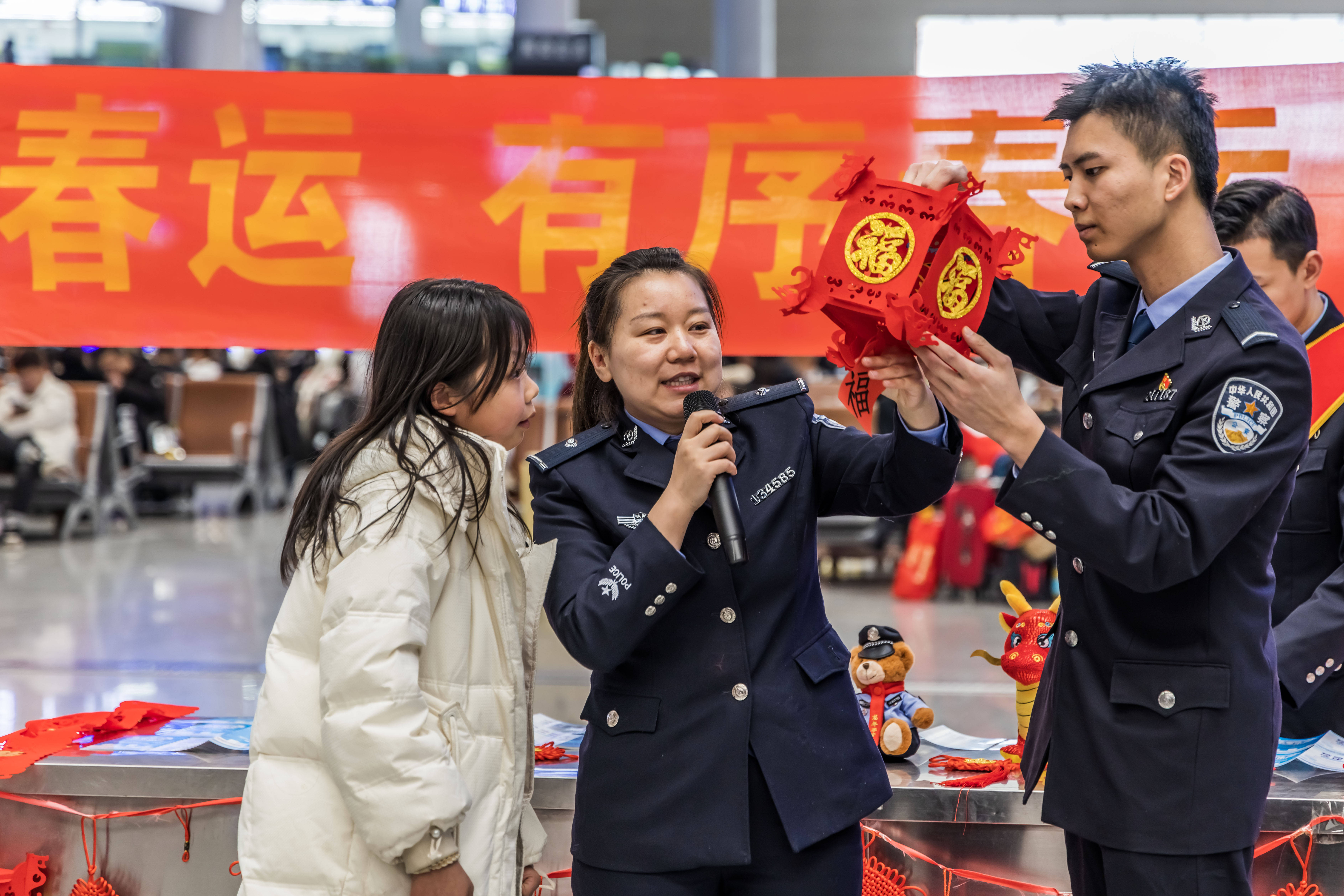 民警将印有"福"字的中国结送给正在候车的小朋友.