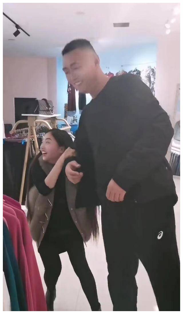 女子在商场内拉着公公的手撒娇,其公公觉得不好意思,急忙想离开