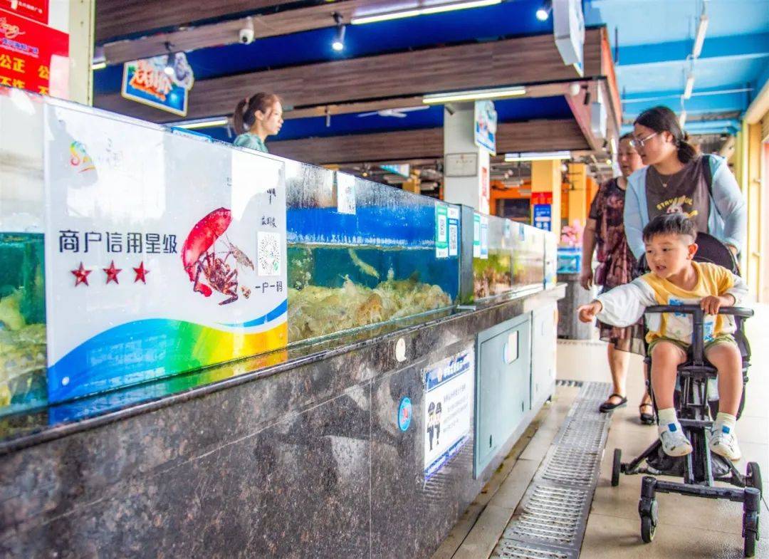 在位于三亚湾的龙兴海鲜广场海鲜销售及加工摊位前,均张贴"商户