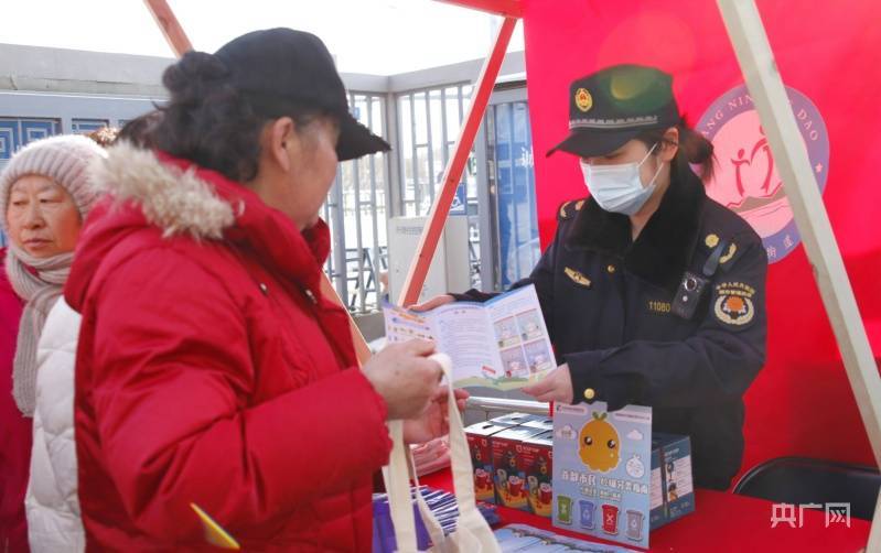 现场设立"扫黄打非"摊位,工作人员向居民分发宣传册(央广网发 广宁