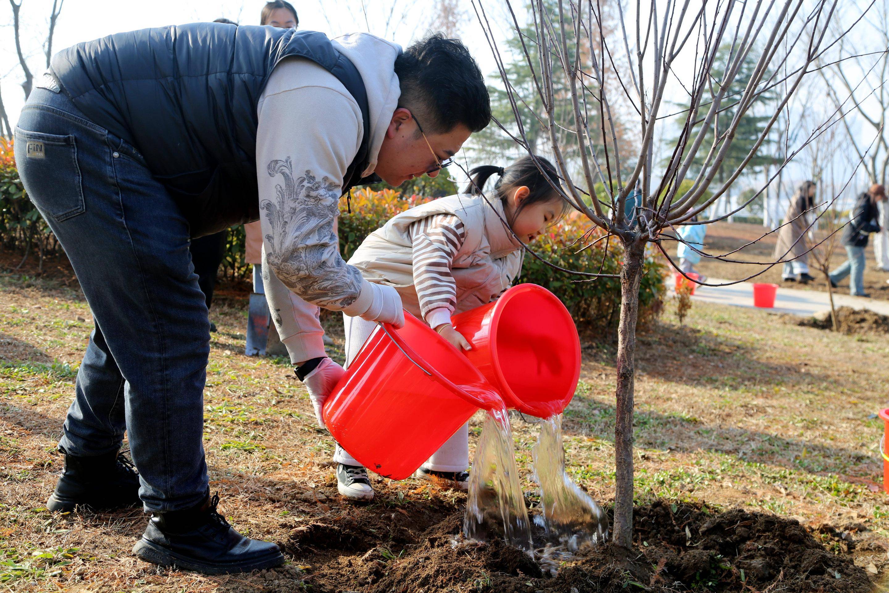 3月9日,家长和小朋友在山东省临沂市兰山区祊河北岸参加植树活动