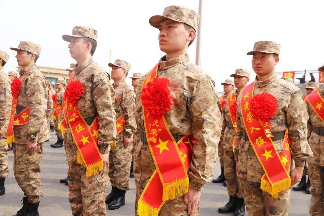 现场气氛热烈,新兵们身着迷彩服,胸带大红花,肩披绶带,英姿飒爽,精神