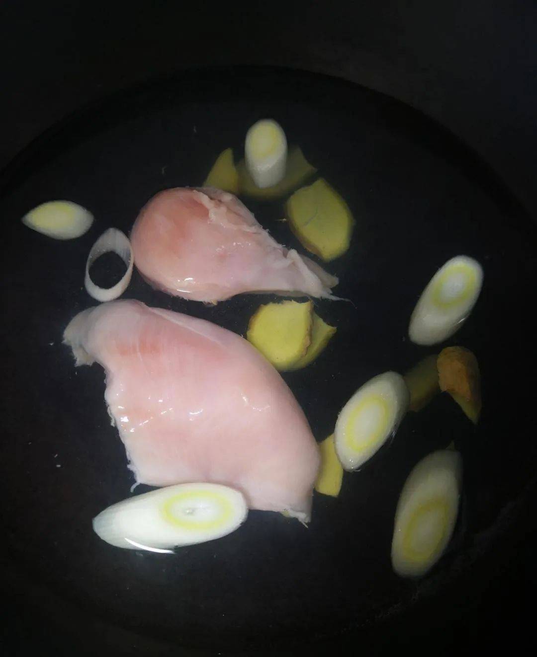 把洗干净的鸡胸肉顺着纹路对半撕开,冷水下锅,加葱,姜.