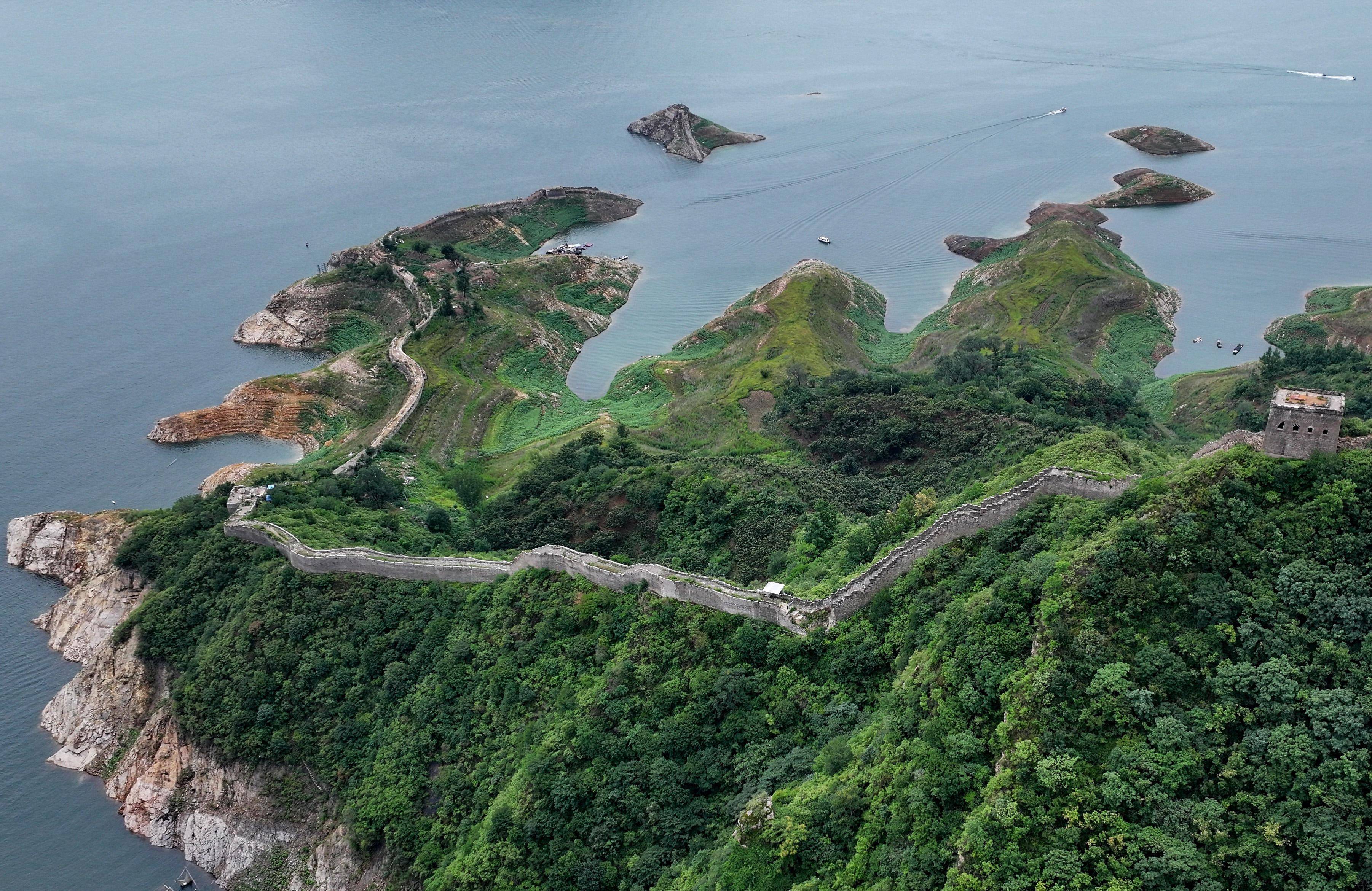 7月13日,在宽城满族自治县境内的潘家口水库,游客在露出水面的长城上