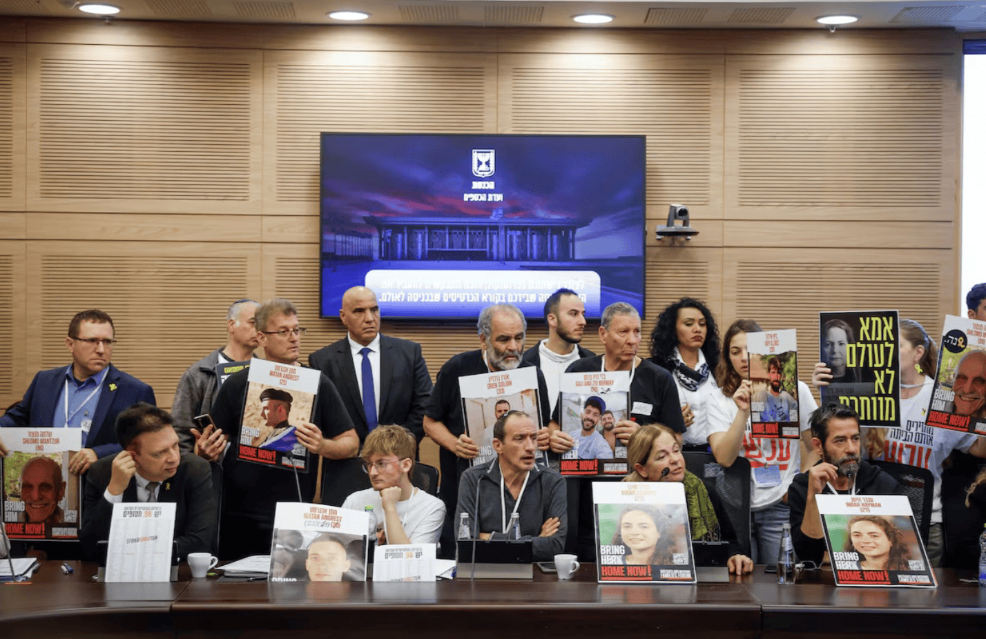 满怀怒火、哭喊恳求！以色列被扣押人员家属手持照片挤进会场谴责以财长