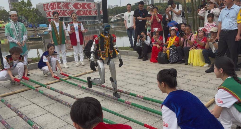 在南宁市的“广西三月三”活动现场，机器人竹竿舞表演吸引游客驻足